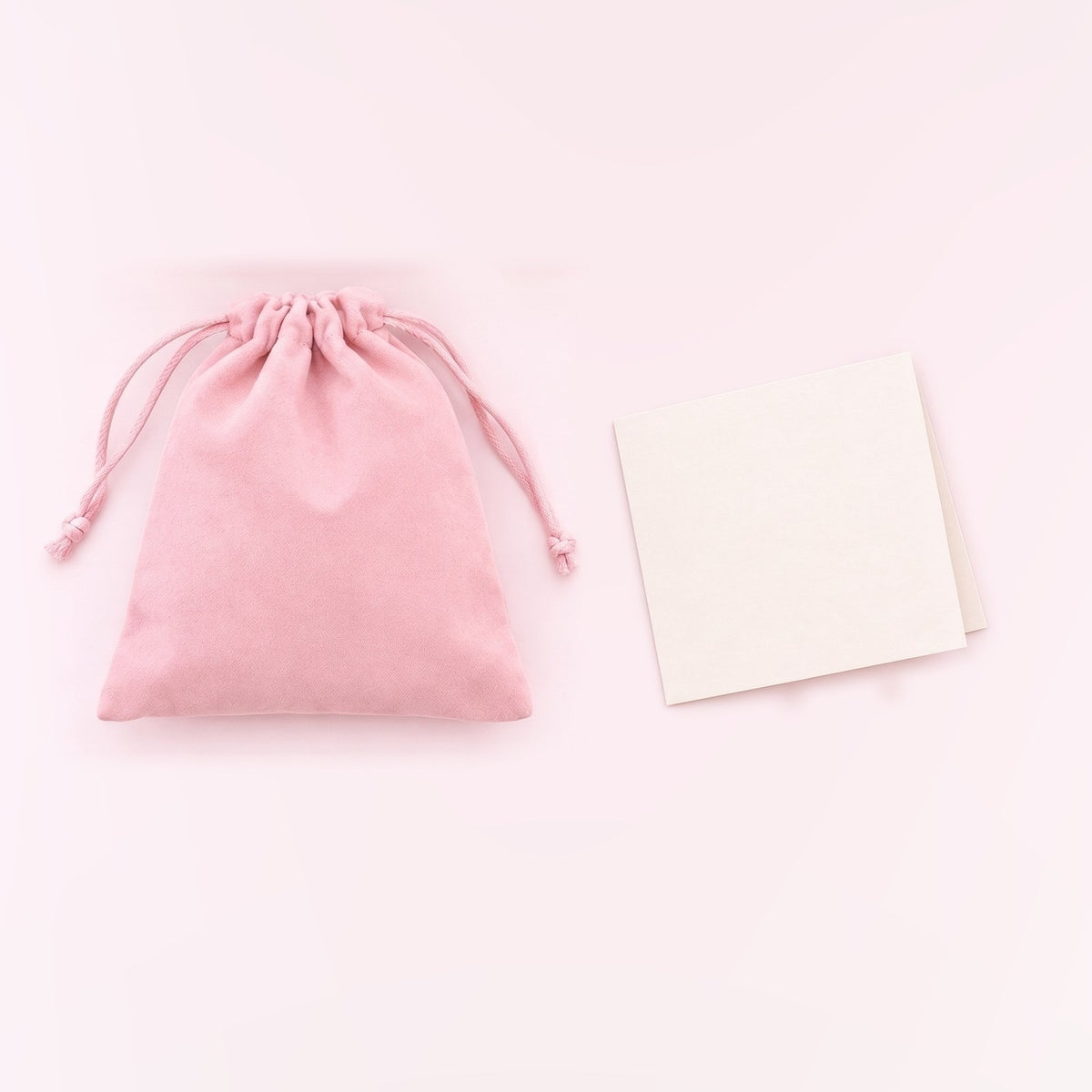 The pink drawstring gift bag next to a blank card